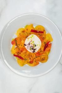 Présentation d'un plat à base de Tomates Burrata dans le restaurant ADMA